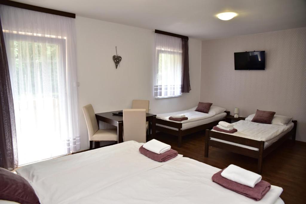 a room with two beds and a table and a couch at Pension U Krbu in Mikulov v Krušných Horách