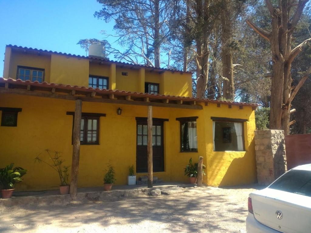 een geel huis met een auto ervoor geparkeerd bij La Casa de la Abuela Tilcara in Tilcara