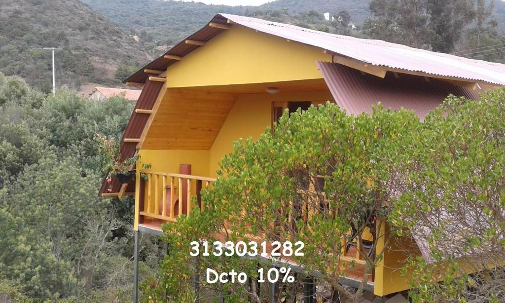 una casa amarilla en una colina con árboles en Cabaña Los Llanitos Guatavita en Guatavita