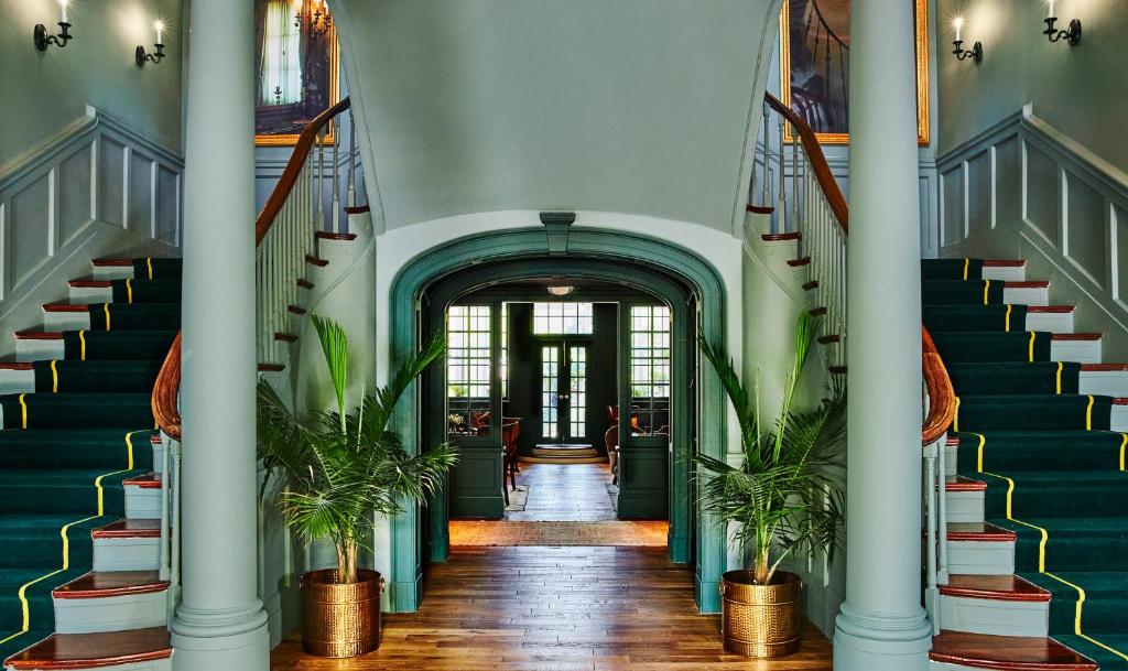 a hallway with stairs and potted plants at The Vanderbilt, Auberge Resorts Collection in Newport