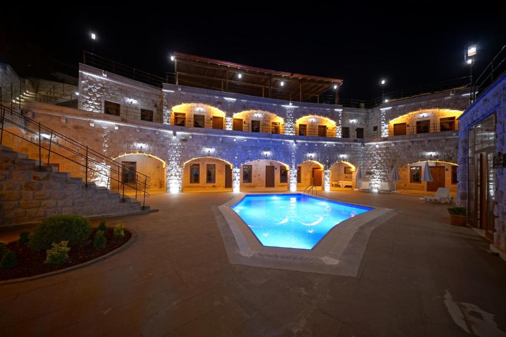 a large courtyard with a swimming pool at night at Göreme Cave Lodge in Göreme