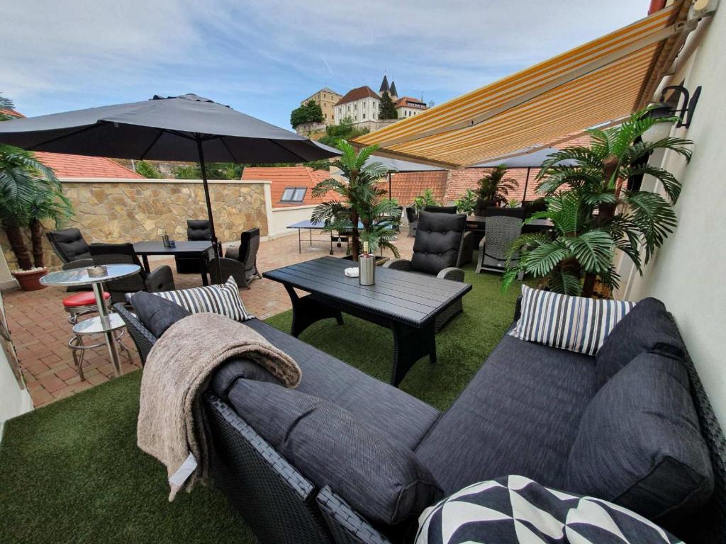 eine Terrasse mit einem Sofa, einem Tisch und einem Sonnenschirm in der Unterkunft A-M Condominium in Veszprém
