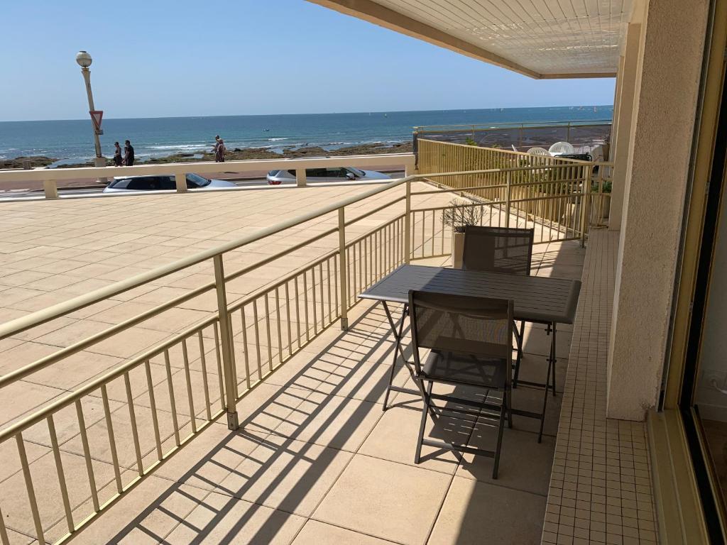 - un balcon avec une table et des chaises sur la plage dans l'établissement Appartement Le Marbella, à Les Sables-dʼOlonne