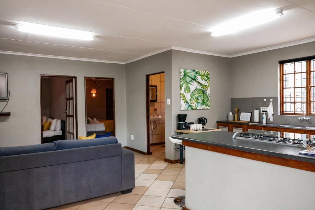 a kitchen and living room with a couch and a counter at Woodii Guest House in Sabie