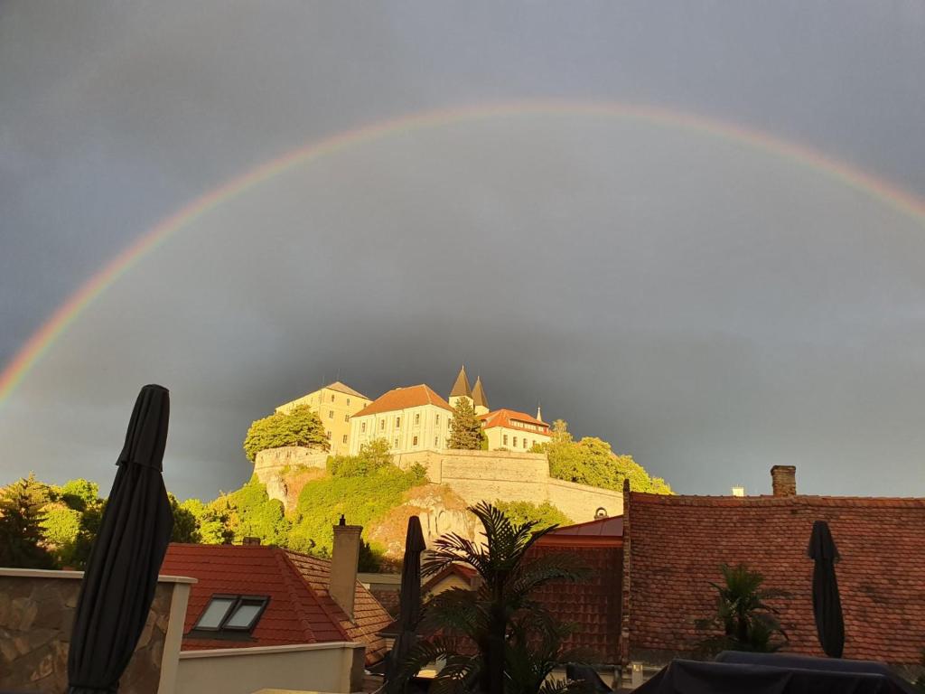 a rainbow over a city with a castle on a hill at A-M Condominium in Veszprém