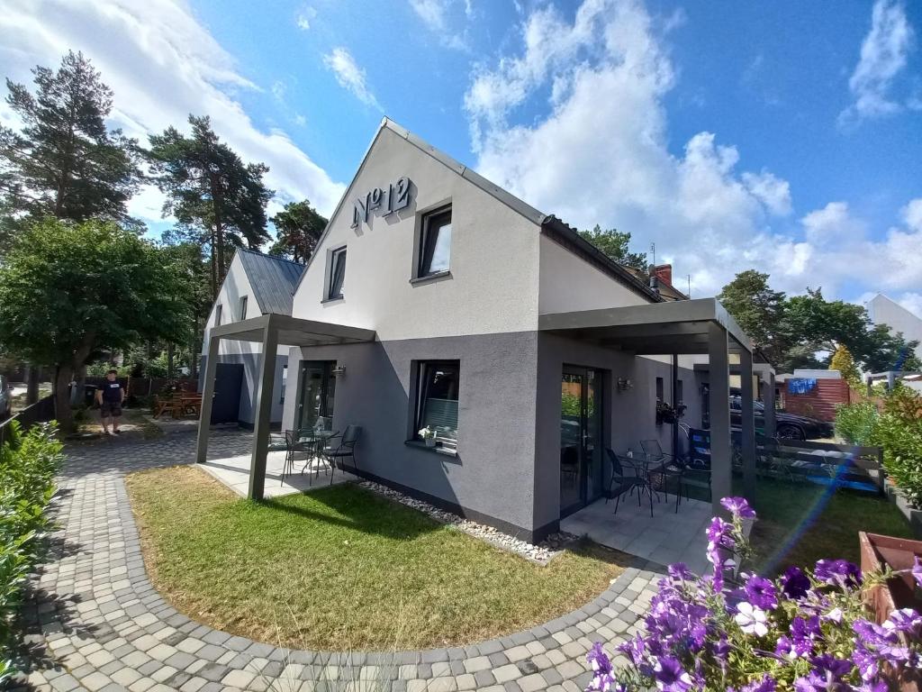 a white house with a yard with purple flowers at No 12 in Pobierowo