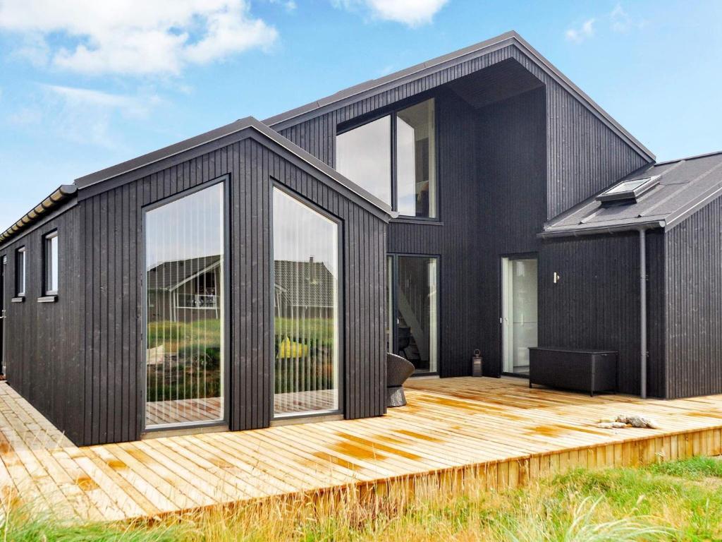 een zwart huis met een houten terras bij 10 person holiday home in Harbo re in Harboør