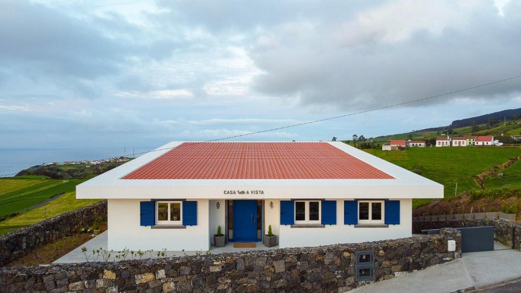 een klein huis met een rood dak op een stenen muur bij Casa Baleia a Vista in Algarvia