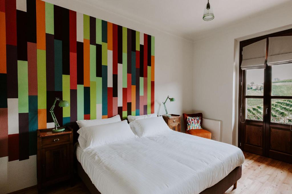a bedroom with a large bed with a colorful wall at La Cascina // Valfaccenda in Canale