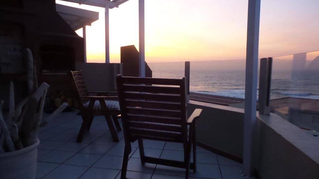 由旺果海灘的住宿－Ocean view at 23 La Crete Sands Uvongo，阳台配有两把椅子和一张桌子,享有海景。