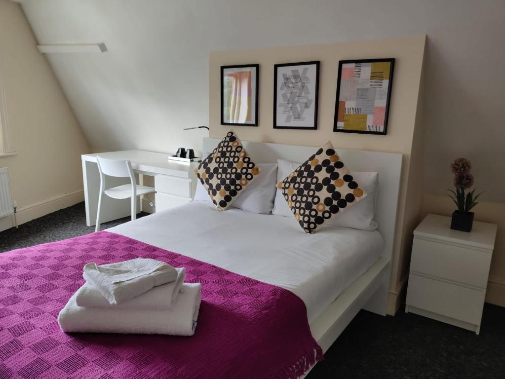 a bedroom with a large bed with a purple blanket at Abbeyfield Guesthouse in Liverpool