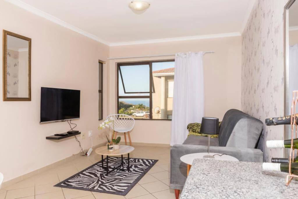 a living room with a couch and a tv at Sun n Surf Sunny and spotless 1 bedroom apartment in Ballito