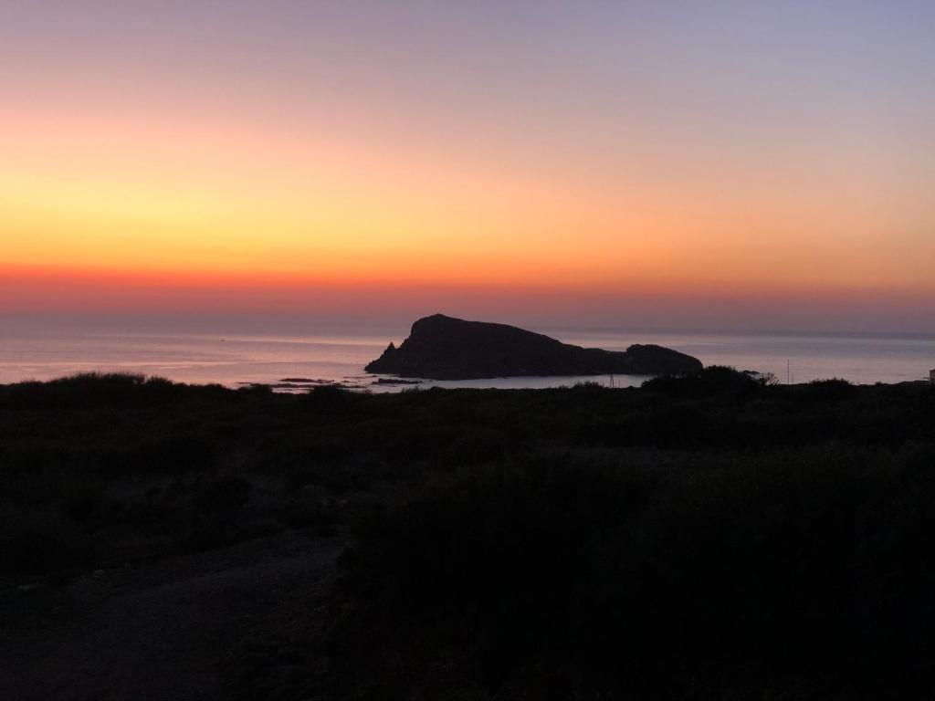 a sunset over the ocean with a rock in the foreground at Résidences Anna in Centuri