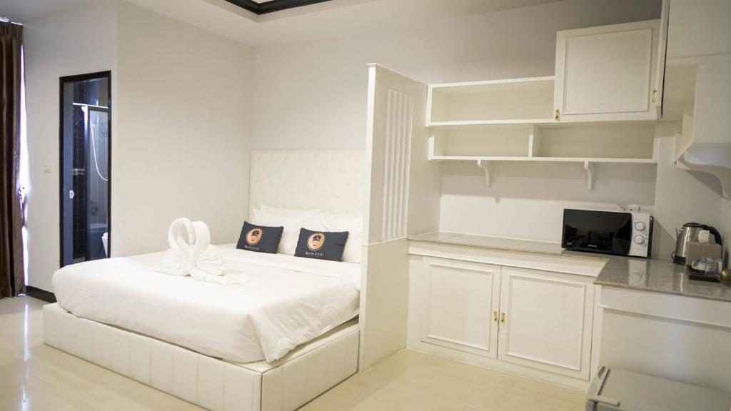 a white bedroom with a bed and a kitchen at RoomQuest Nichada ISB International in Ban Bang Talat