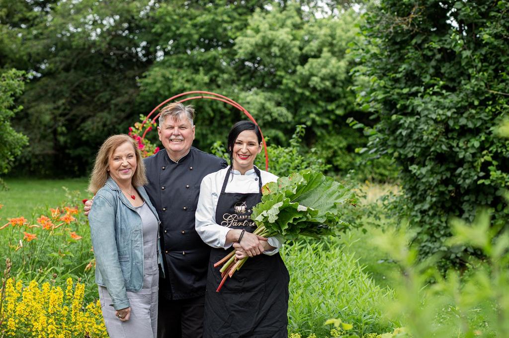 Ein Mann und zwei Frauen stehen in einem Garten in der Unterkunft Landhotel Restaurant Gärtner in Mücke