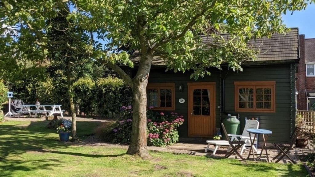 een klein huis met een picknicktafel en een boom bij Captivating 1-Bed Log Cabin in Shrewsbury in Shrewsbury