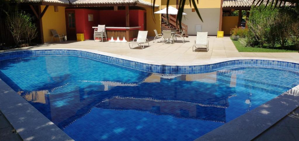 una gran piscina azul con sillas alrededor en Paz & Diversão Praia Do Forte, en Praia do Forte