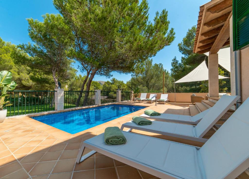 een zwembad met tuinmeubilair en een zonneklep bij Villa Cala Mesquida in Cala Mesquida