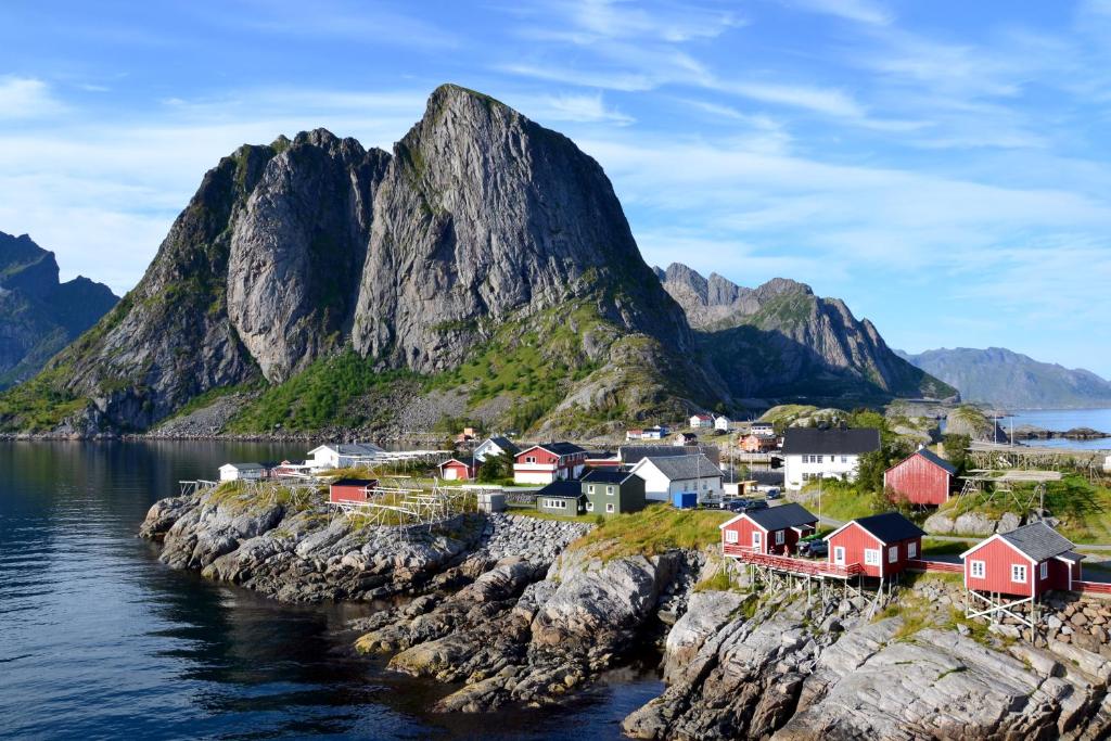 een dorp aan de oever van een waterlichaam met bergen bij The Manor House in Hamnøy in Reine