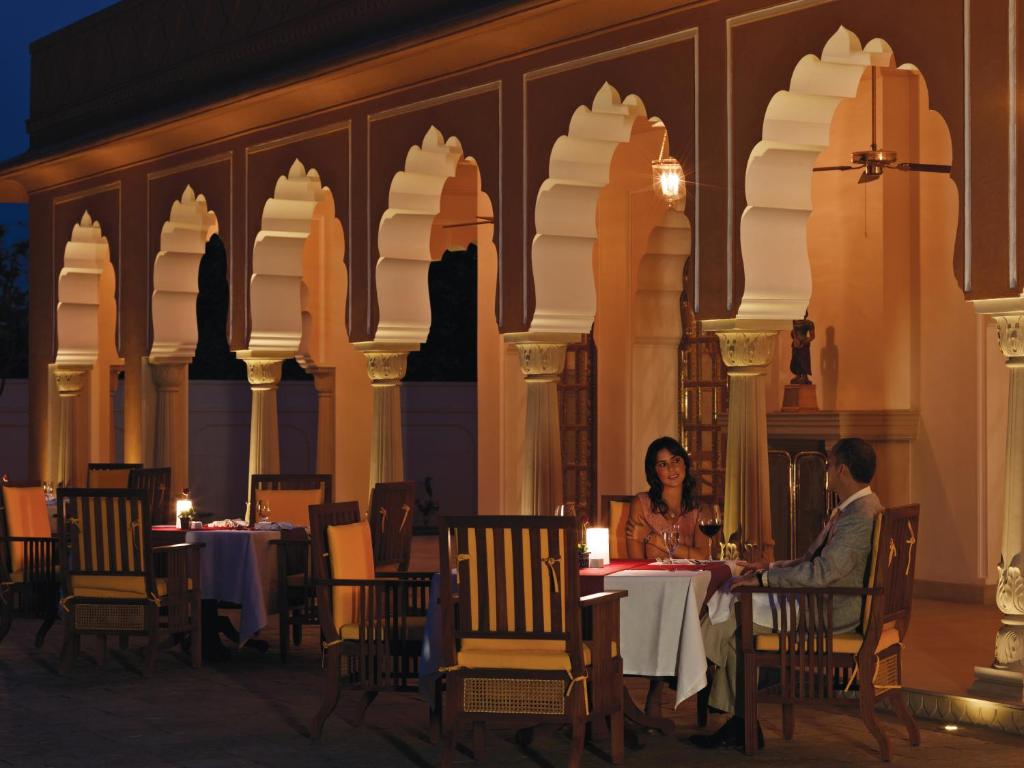 a woman sitting at a table in front of a large clock tower at The Oberoi Rajvilas Jaipur in Jaipur