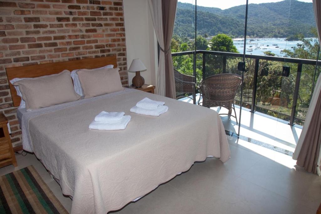 a bedroom with a bed and a balcony with a view at ATLANTIC FOREST ROOM in Angra dos Reis