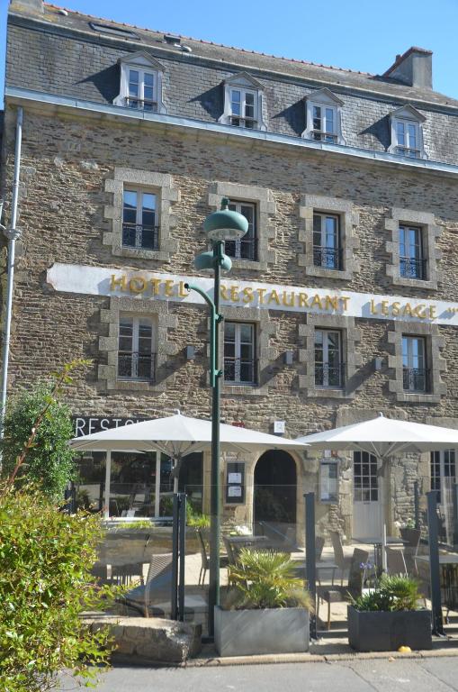 un bâtiment avec des tables et des parasols devant lui dans l'établissement Hotel Restaurant Lesage, à Sarzeau