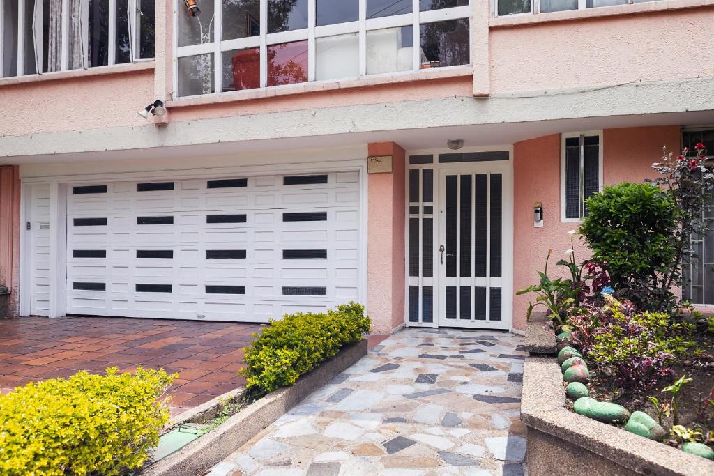 una casa con puertas blancas de garaje y una entrada de ladrillo en Touristic House, en Bogotá