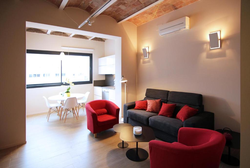 uma sala de estar com um sofá preto e cadeiras vermelhas em Barcelona InLoft em Barcelona
