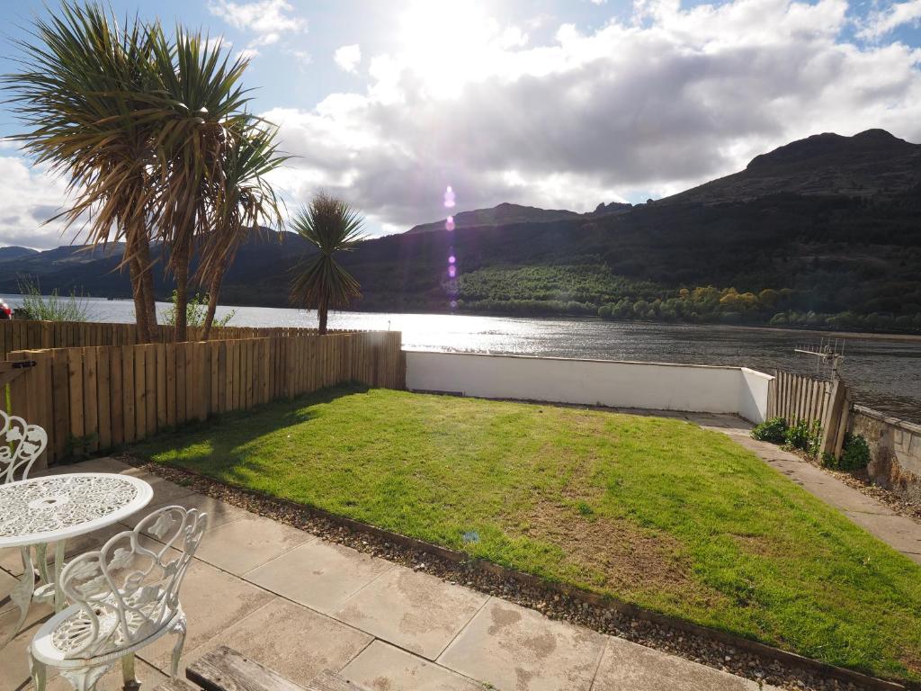 a patio with a table and chairs and a view of a lake at Arrochar Alps Apartment in Arrochar