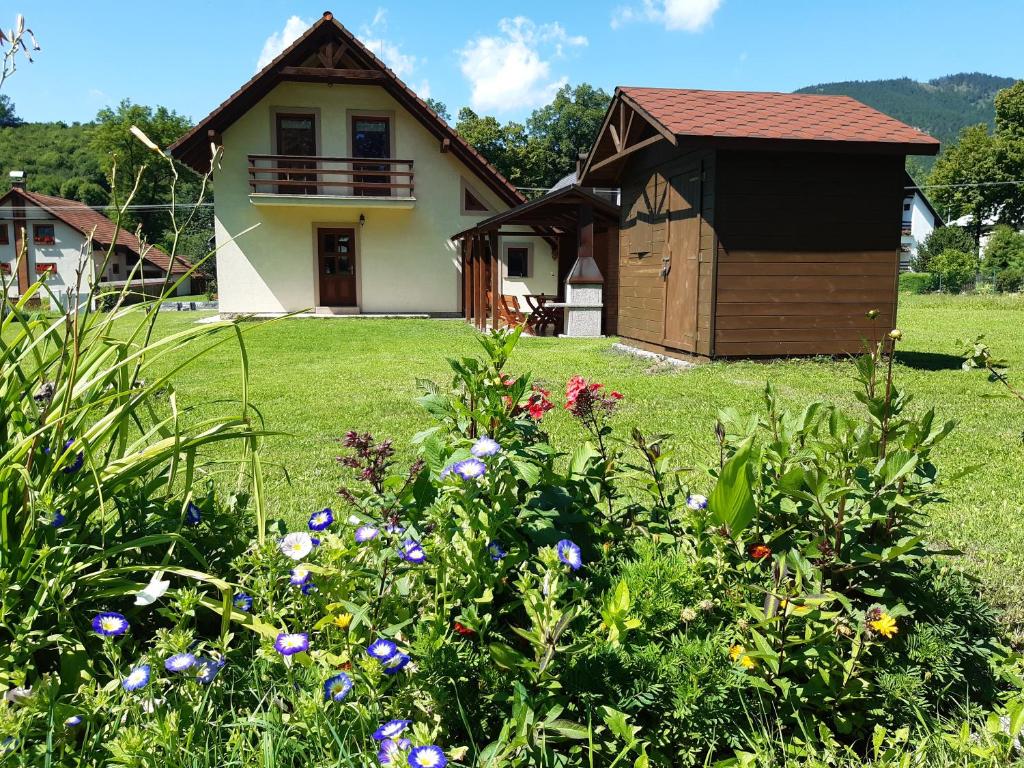 une maison avec une cour fleurie devant elle dans l'établissement Chata Monika, à Prosiek