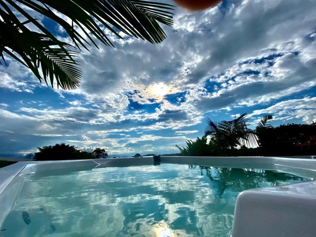 a swimming pool with a cloudy sky in the background at Las Palmas Finca Turística in Filandia