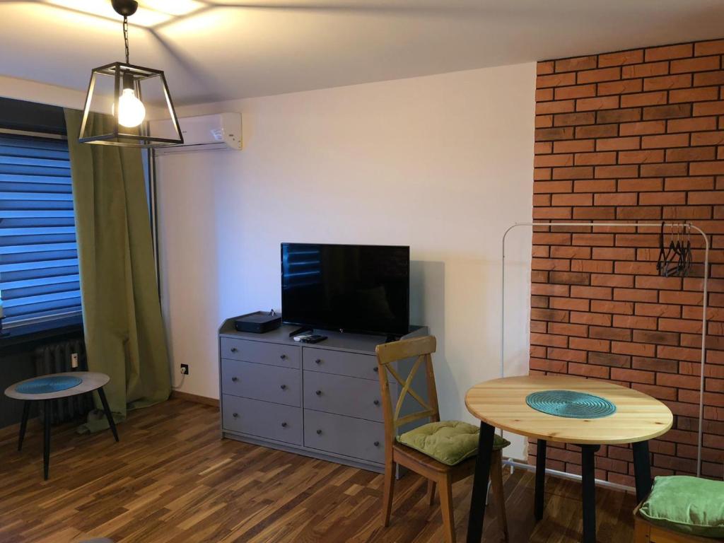 Studio Rynkowa في شتتين: غرفة معيشة مع طاولة وتلفزيون وطاولة وكراسي