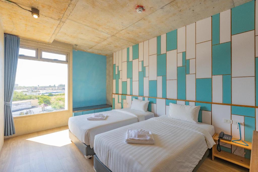Duas camas num quarto com uma janela grande em EcoLoft Hotel - SHA Plus em Cidade Phuket