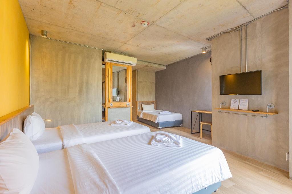 um quarto de hotel com duas camas e uma televisão em EcoLoft Hotel - SHA Plus em Cidade Phuket
