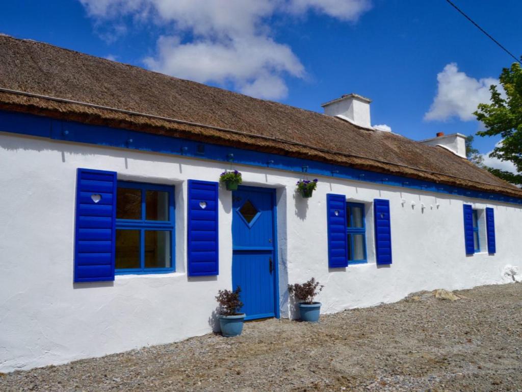 a blue and white house with blue shutters at Beautiful Thatched Adderwal Cottage Donegal in Doochary