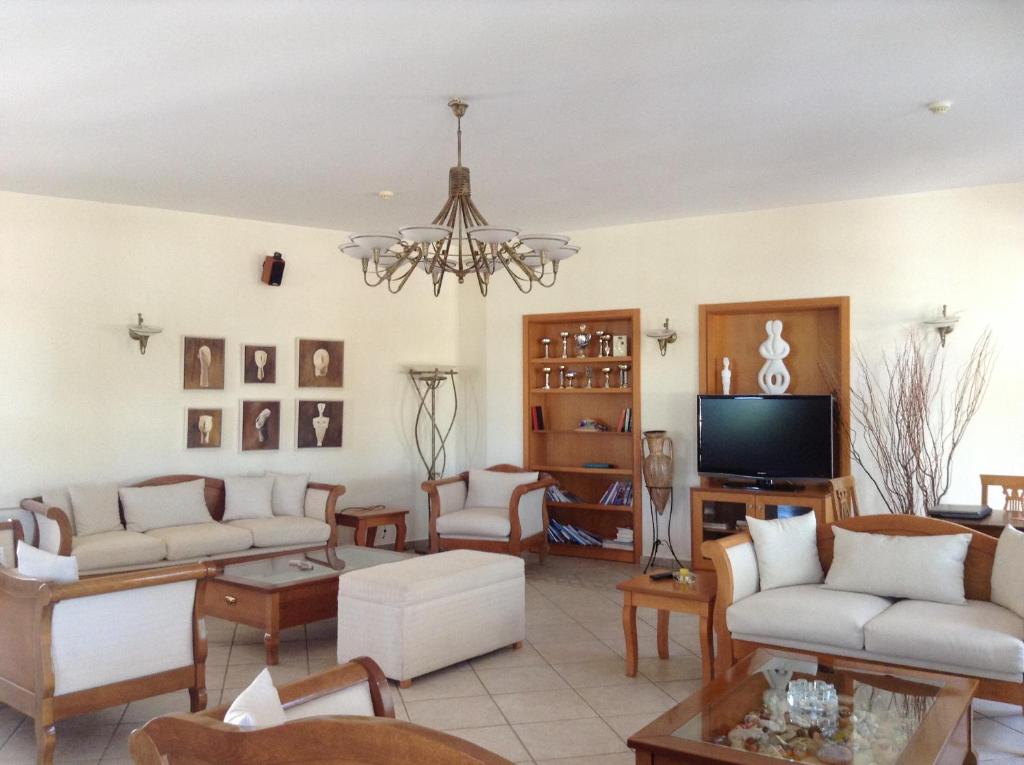 a living room with white furniture and a chandelier at Astir Of Naxos in Naxos Chora