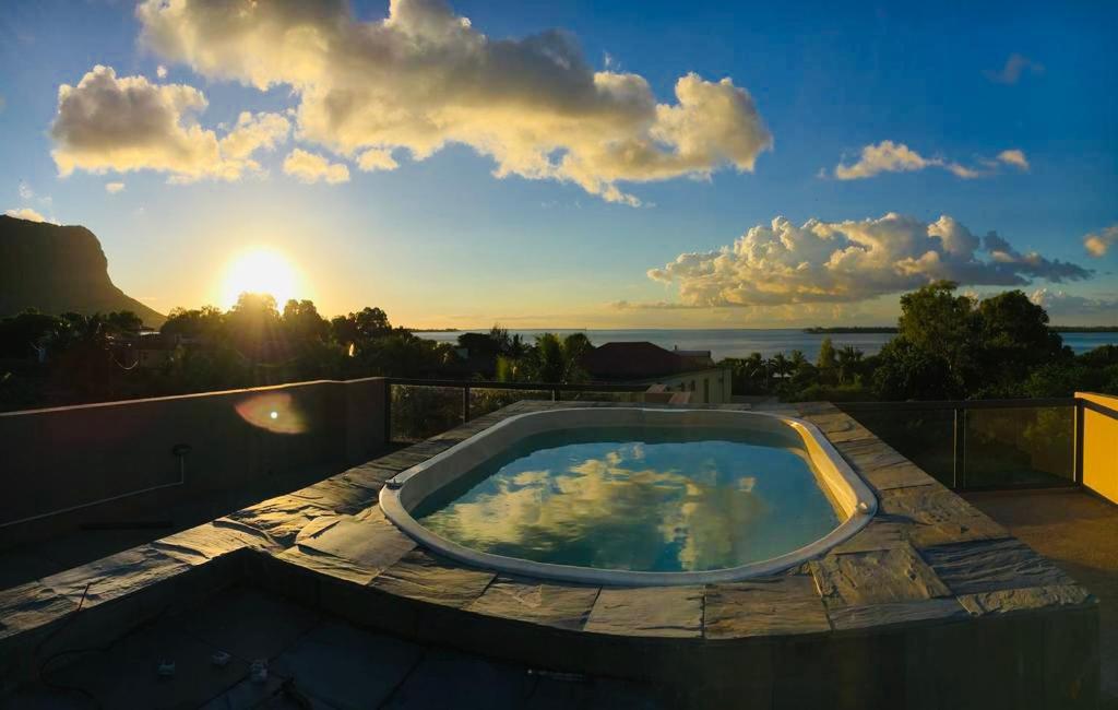 bañera de hidromasaje en un balcón con vistas a la puesta de sol en Luxe Exotica Apartments, en La Gaulette