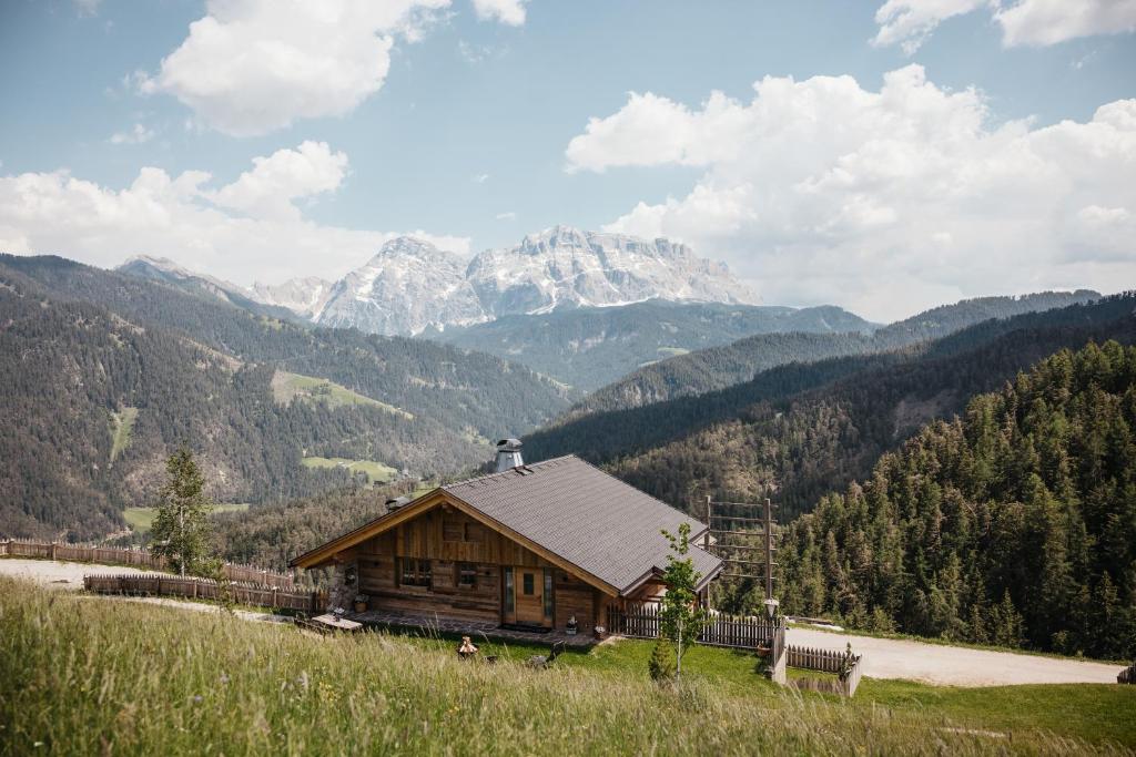 a log cabin on a hill with mountains in the background at Chalet Rich in Val Badia in San Martino in Badia
