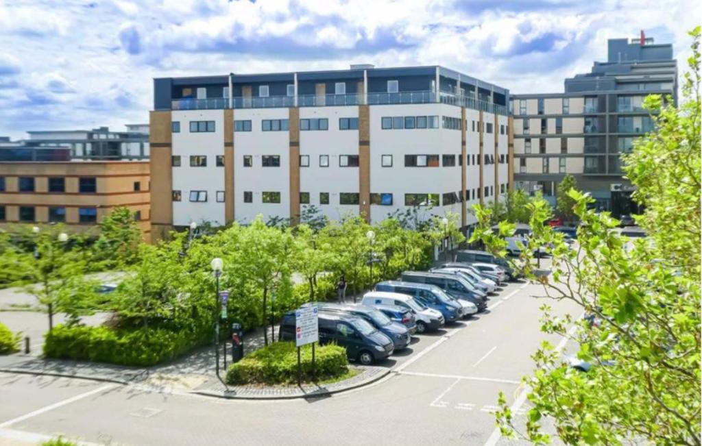 um parque de estacionamento com carros estacionados em frente a um edifício em Blue Sapphire em Milton Keynes
