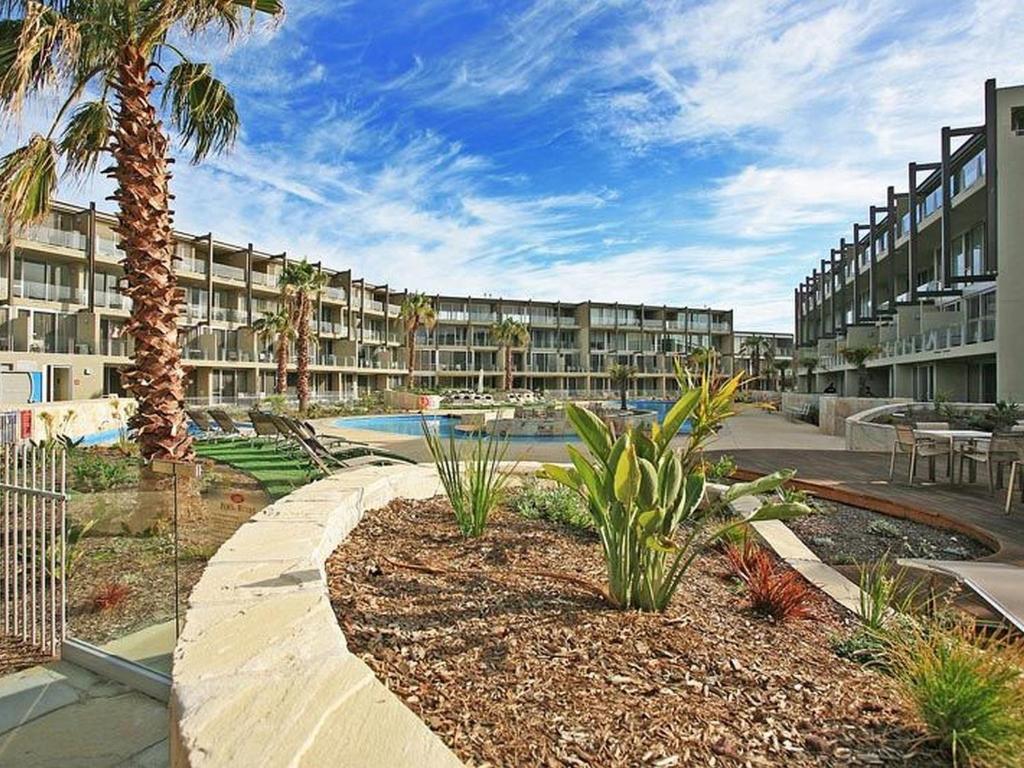 a large apartment complex with a swimming pool and palm trees at Resort Hotel Room 261 in Torquay