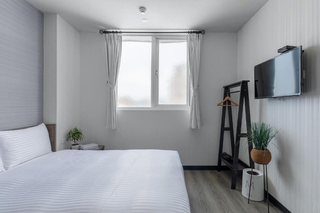 Schlafzimmer mit einem Bett und einem Flachbild-TV in der Unterkunft Hotel Brown - Zhongzheng in Tainan