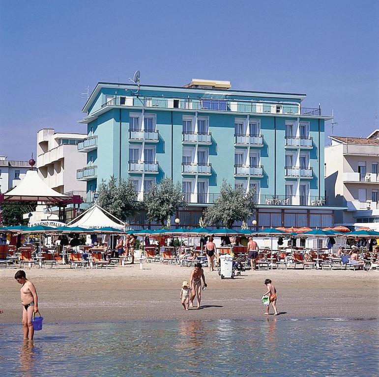 un grupo de personas en una playa con un edificio azul en Hotel Gradara, en Bellaria-Igea Marina