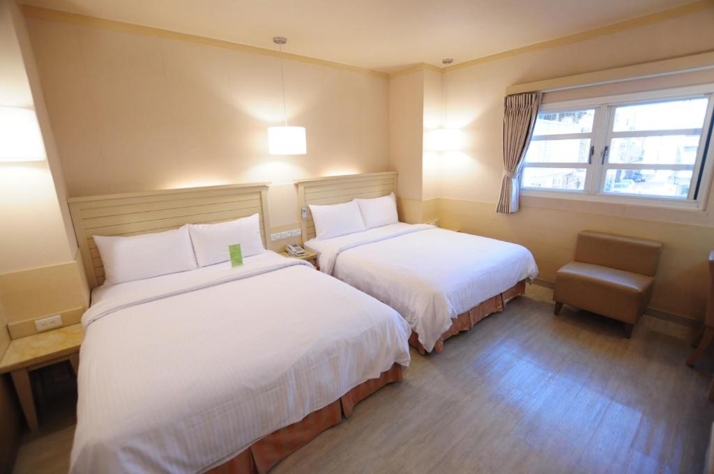 a hotel room with two beds and a window at Kindness Hotel - Tainan Minsheng in Tainan