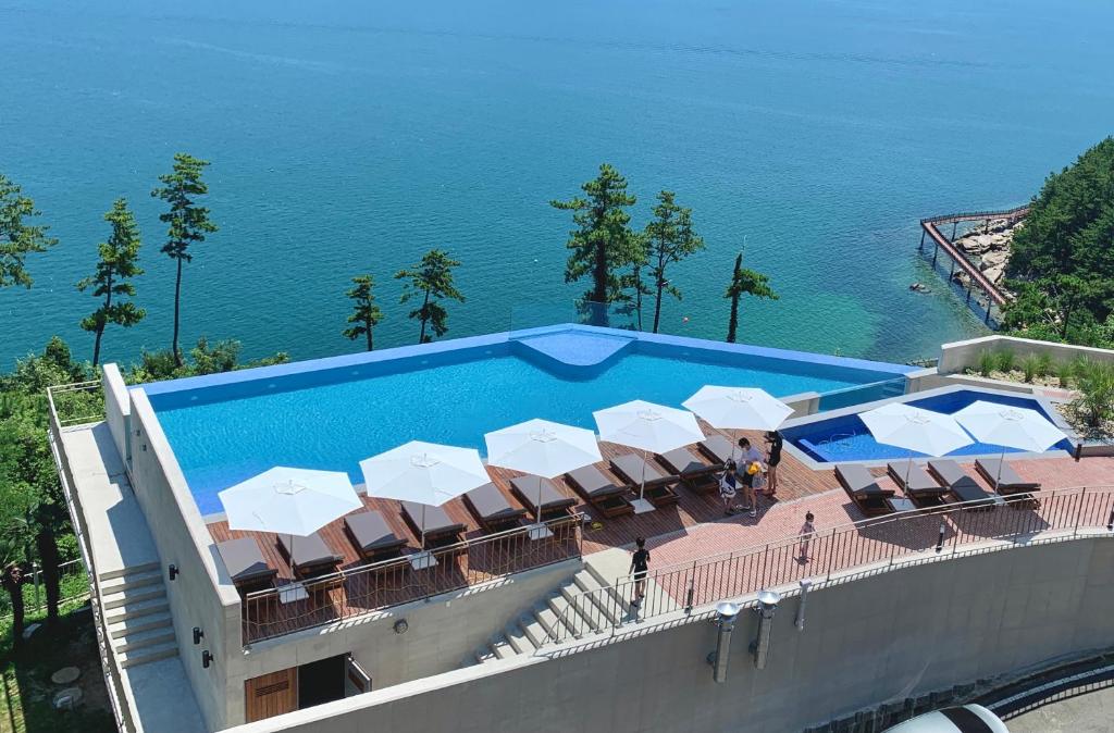 a swimming pool with chairs and umbrellas next to the ocean at Hotel SANG SANG in Geoje