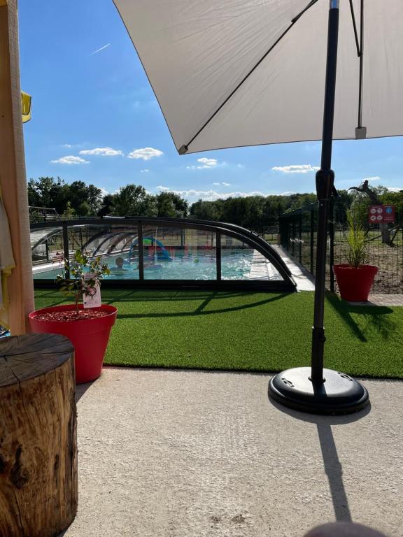 a patio with an umbrella and a view of a pool at La Petite Ferme in Mazé