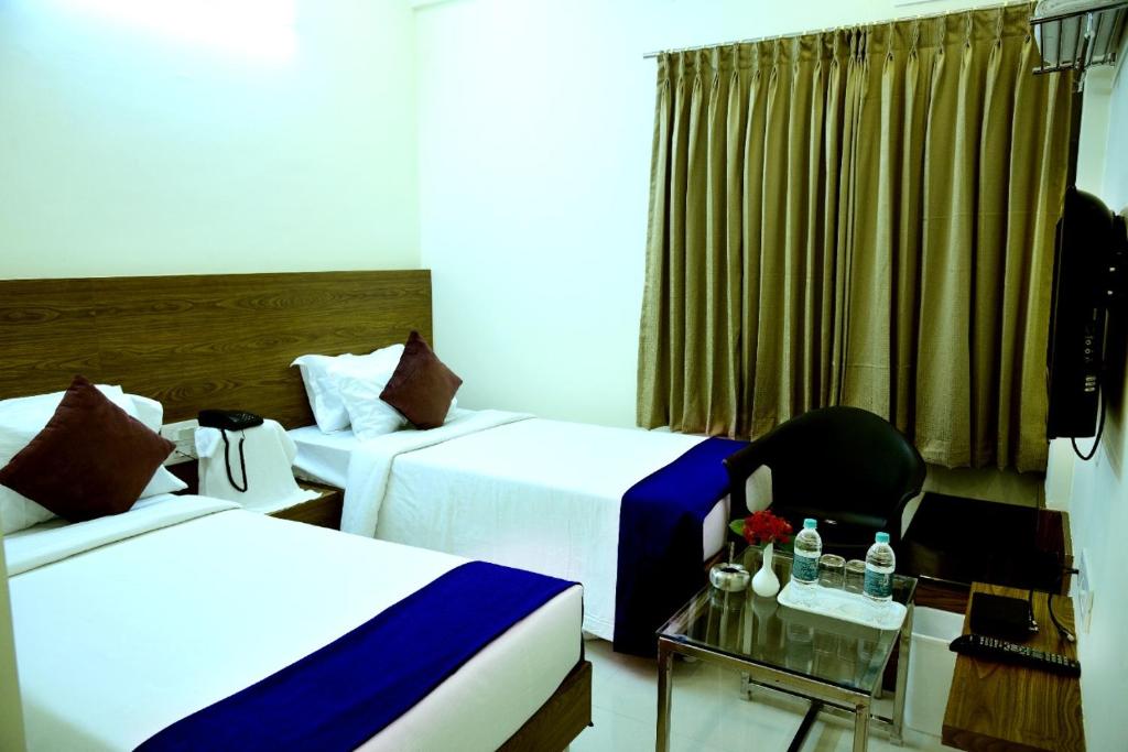 um quarto de hotel com duas camas e uma cadeira em Vismaya Comforts em Mysore