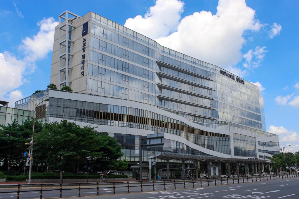 duży szklany budynek z ulicą przed nim w obiekcie Novotel Ambassador Suwon w mieście Suwon