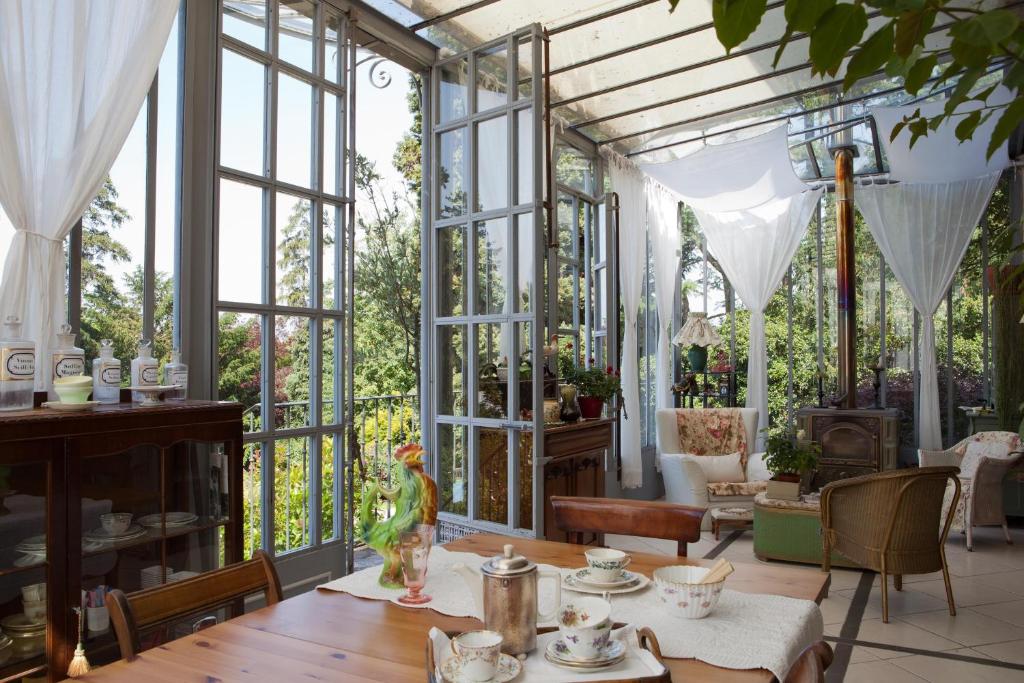 une véranda avec une table, des chaises et des fenêtres dans l'établissement La Pluie de Roses, à Giverny