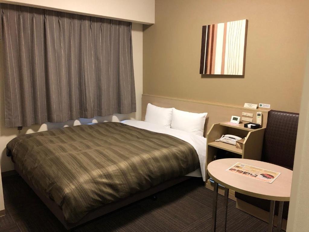 ein Hotelzimmer mit einem Bett und einem Tisch in der Unterkunft Hotel Route Inn Hashimoto in Hashimoto