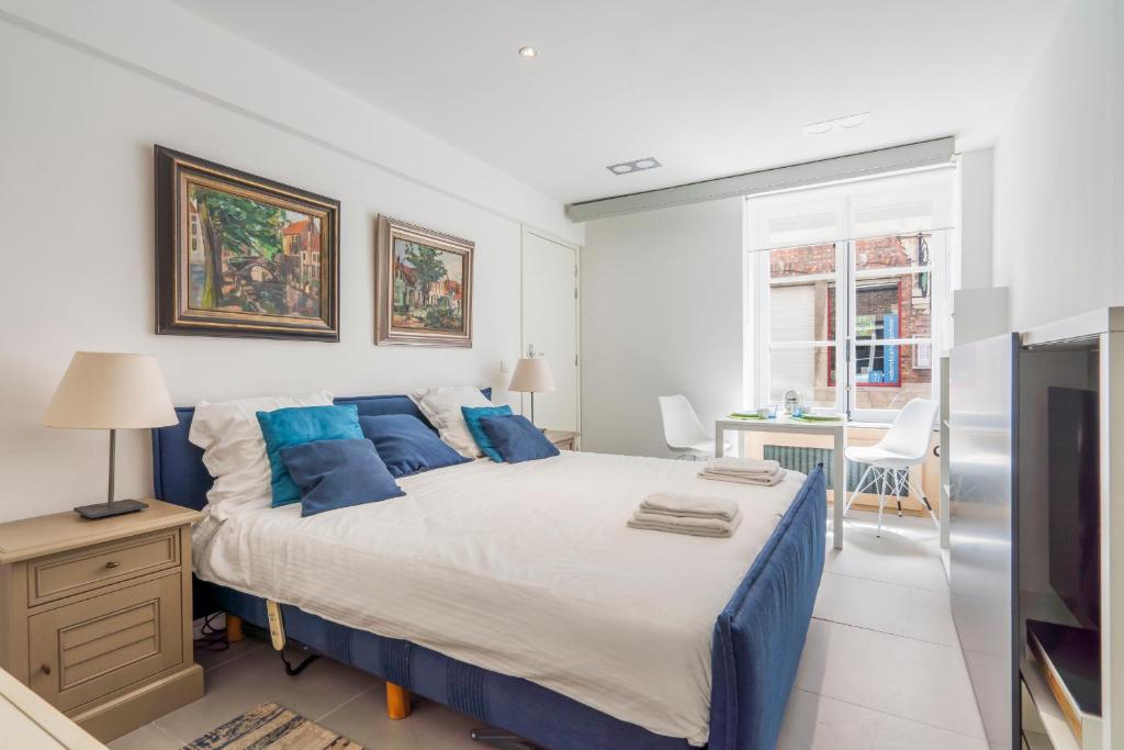een slaapkamer met een groot bed met blauwe kussens bij Modern guest house in centre of Bruges in Brugge